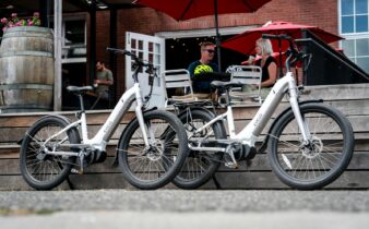 A Pair of White Electric Bikes Parked Near Couple Sitting Outside a Restaurant