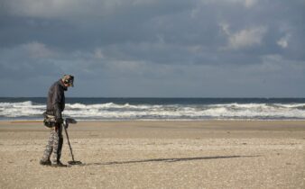 man in black jacket and black pants holding black dslr camera on beach during daytime