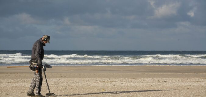 man in black jacket and black pants holding black dslr camera on beach during daytime