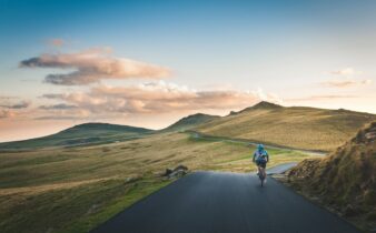 person cycling on road distance with mountain during daytime